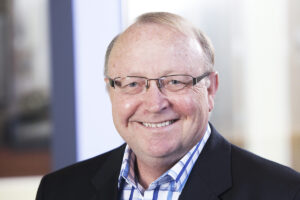 Professional headshot of Dr. Jim Mahoney, educational leadership expert; subject is seated and smiling at the camera.